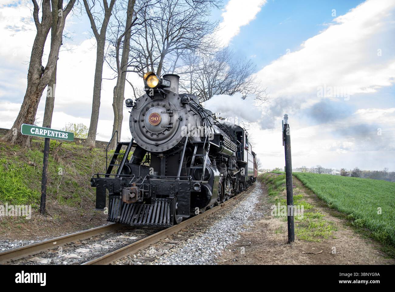 Ronks, Pennsylvania, 15 aprile 2025 - Una storica locomotiva a vapore si snoda lungo la ferrovia vicino a Carpenters, circondata da vegetazione lussureggiante e alberi, con Foto Stock
