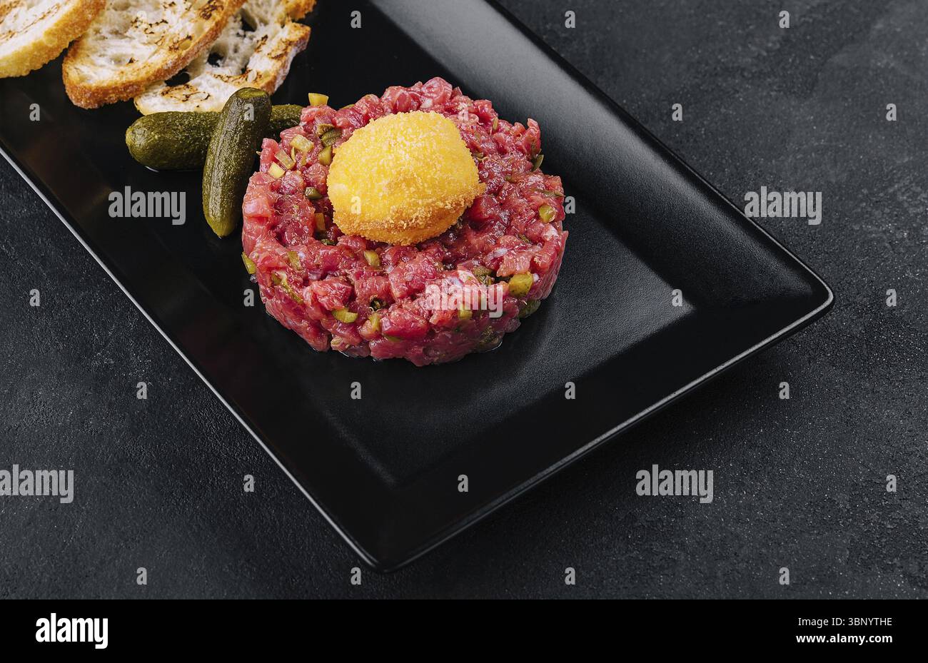 Natura morta, tartare di manzo con cetrioli salati e pane alla griglia Foto Stock