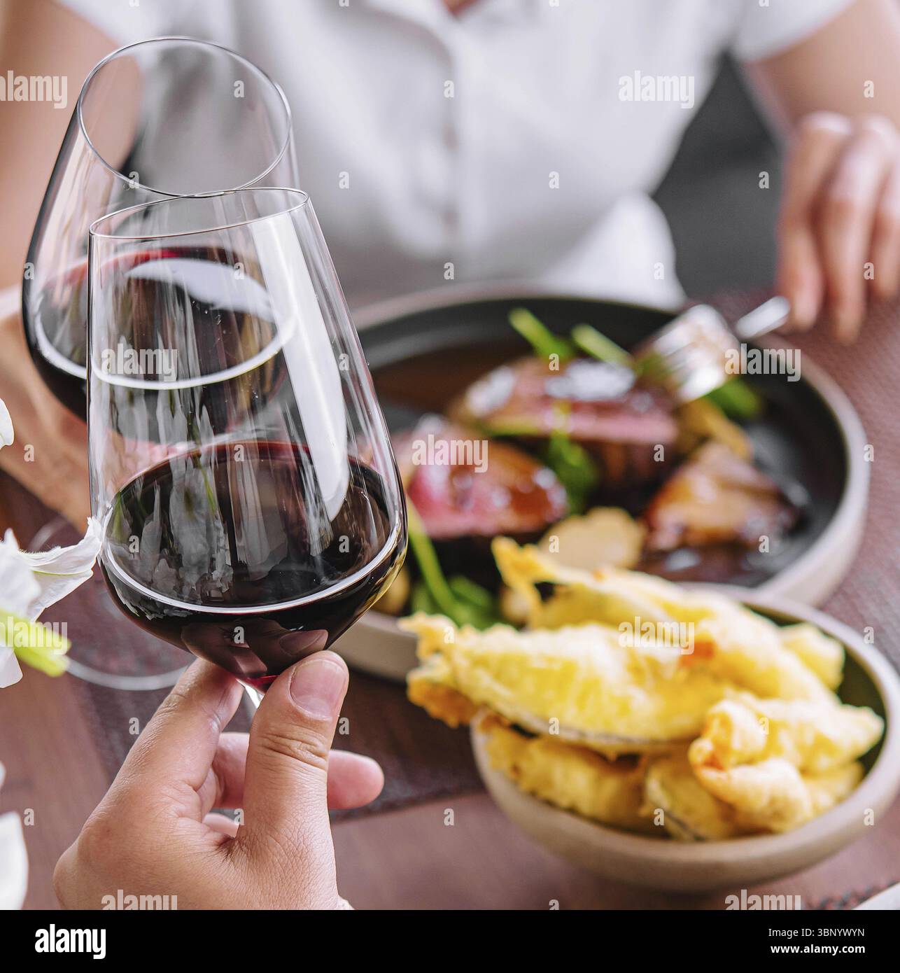 Uomo e donna bevono vino rosso al ristorante Foto Stock