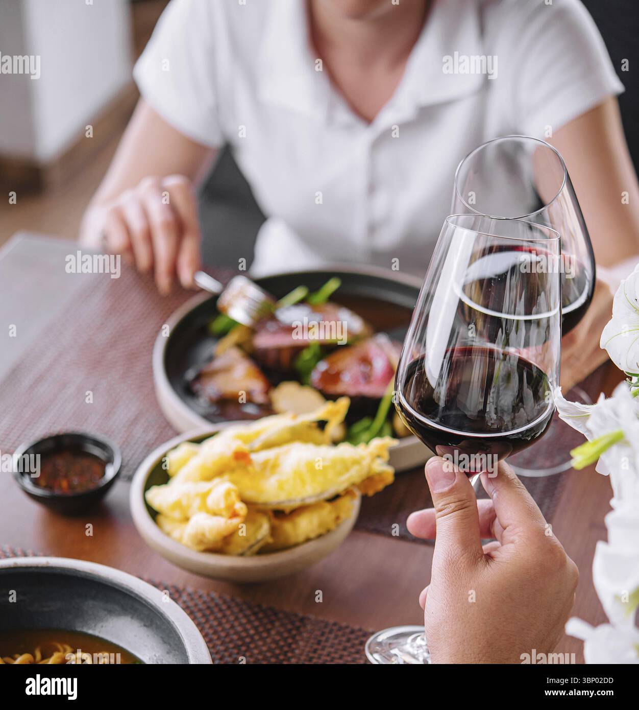 Uomo e donna bevono vino rosso al ristorante Foto Stock