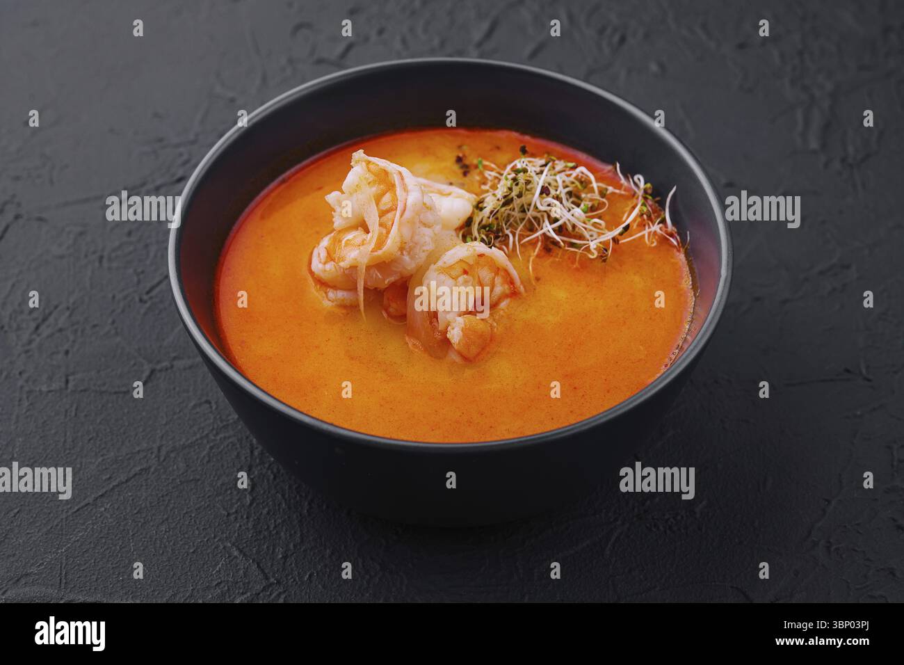 Cibo natura morta, tradizionale zuppa tailandese Tom Yam in ciotola nera Foto Stock