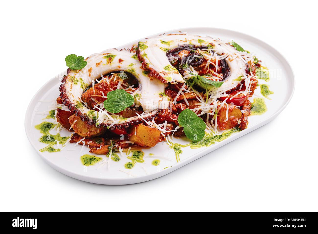 Natura morta alimentare, i tentacoli di polpo grigliati si trovano in cima a un letto di verdure arrostite, guarniti con erbe e formaggio su un piatto bianco, evidenziando un colo Foto Stock