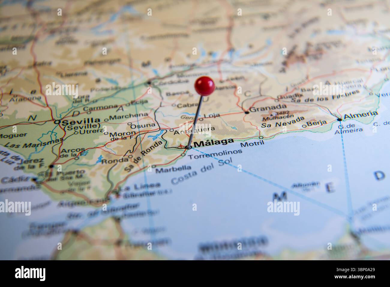 Primo piano di una spilla rossa che segna la città di Málaga su una mappa mondiale dell'atlante della Spagna, che rappresenta la pianificazione del viaggio, la destinazione e l'esplorazione Foto Stock