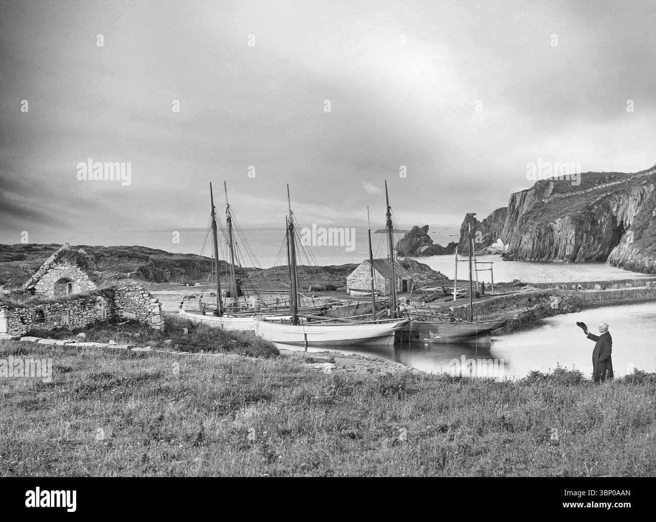 Una fotografia della fine del XIX secolo di barche a vela nel porto meridionale di Cape Clear Island al largo della costa sud-occidentale della contea di Cork in Irlanda. Il sacerdote a destra sta sventolando verso le rovine di una chiesa del XII secolo. Foto Stock