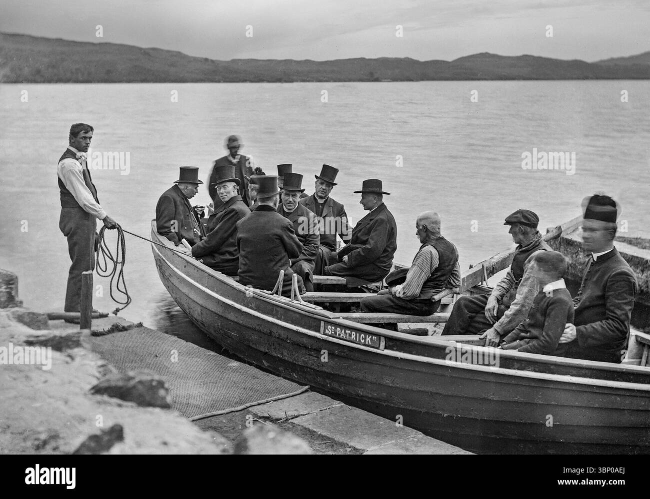 Una fotografia del cardinale Logue all'inizio del XX secolo a Lough Derg circondata da dignitari con il prete locale nella prua della barca. Lungo il tragitto per Inis Cealtra, nota anche come Inishcaltra o Holy Island, un'isola al largo della costa occidentale di Lough Derg in Irlanda, un tempo un insediamento monastico, ora disabitato, è un luogo di pellegrinaggio. Foto Stock