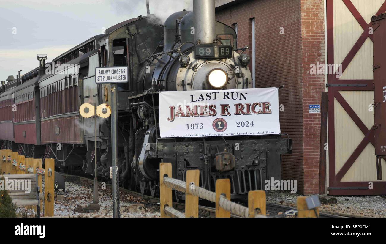 Strasburg, Pennsylvania, 31 dicembre 2024 - Un treno a vapore d'epoca viaggia attraverso un paesaggio rurale, mostrando un cartello in omaggio a James R. Rice du Foto Stock