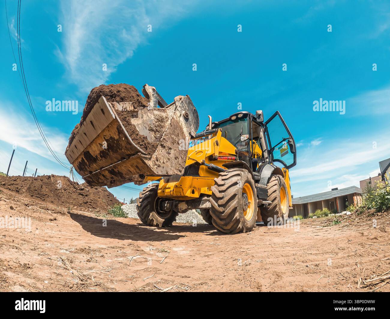 La grande pala gialla del trattore consente di livellare un terreno per un nuovo edificio. Preparazione del cantiere. Livellamento orizzontale Foto Stock