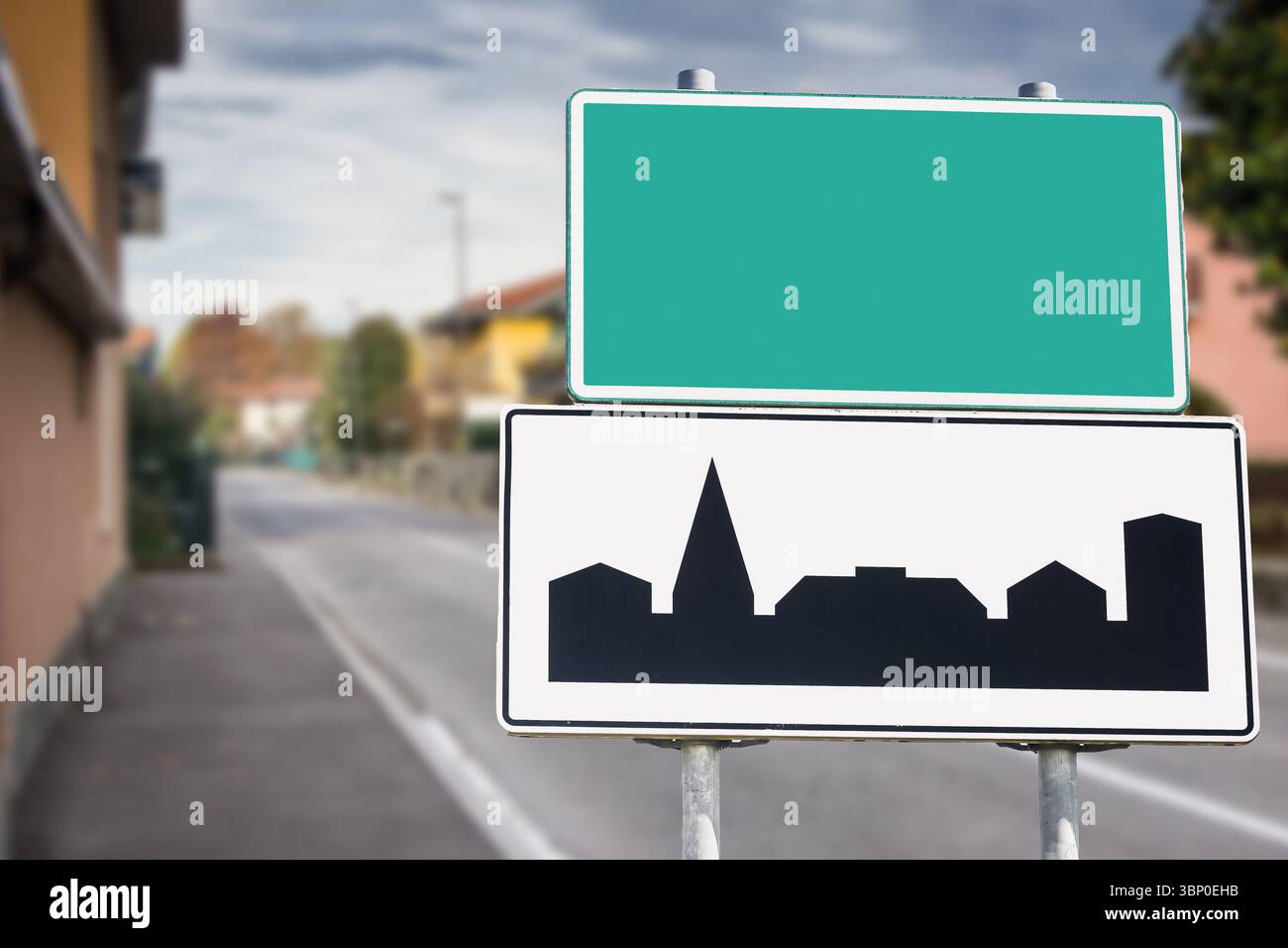 Cartello d'ingresso della città vuoto e sagoma degli edifici. Strada con case residenziali sullo sfondo. Simbolo del confine della zona urbana. Scheda nome luogo vuota. Foto Stock