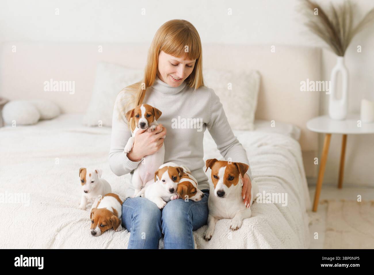 Donna e cuccioli a casa mostrano amore per gli animali, cura degli animali, calore e legame, catturando un momento di gioia in famiglia. Foto Stock