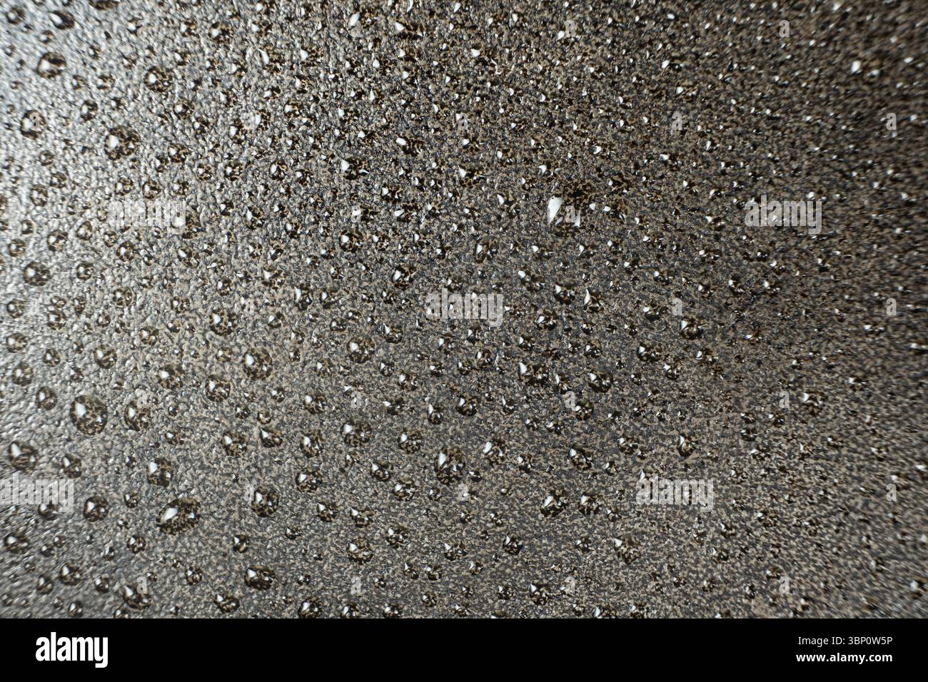 Gocce d'acqua su una superficie macro in ghisa. Cura delle pentole in ghisa, resistente alla ruggine, modello astratto. Foto Stock