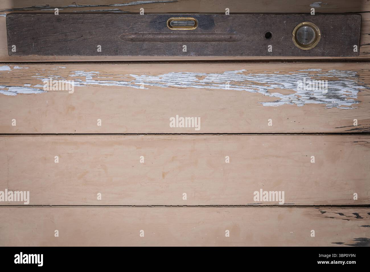 Una livella a bolla d'aria in legno molto vecchia collocata sul bordo superiore di un tavolo di legno beige. Il resto della cornice lascia molto spazio vuoto per il testo o la progettazione. Foto Stock