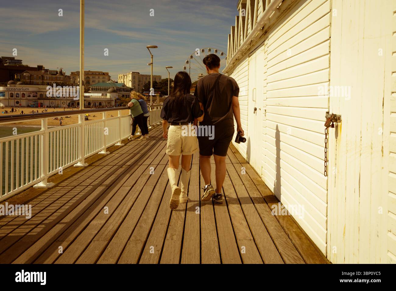 Coppia che cammina lungo le tavole di legno del molo di Bournemouth Foto Stock