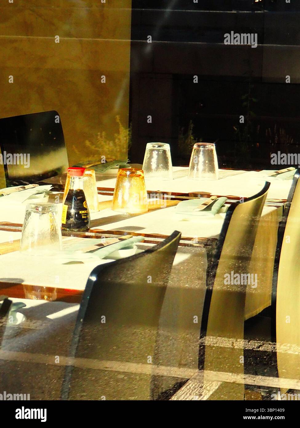Bottiglia di salsa di soia sul tavolo illuminato dal sole nel ristorante giapponese, all'interno di Milano con riflessi Foto Stock