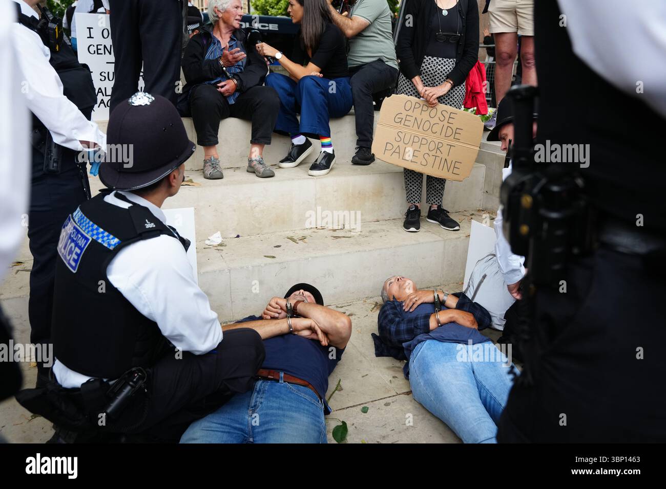 Gli agenti della polizia metropolitana allontanano le persone da una protesta a sostegno dell'azione palestinese, organizzata dal gruppo Difendi Our Juries, di fronte alla statua del Mahatma Gandhii in Parliament Square, nel centro di Londra. Data foto: Sabato 5 luglio 2025. Foto Stock