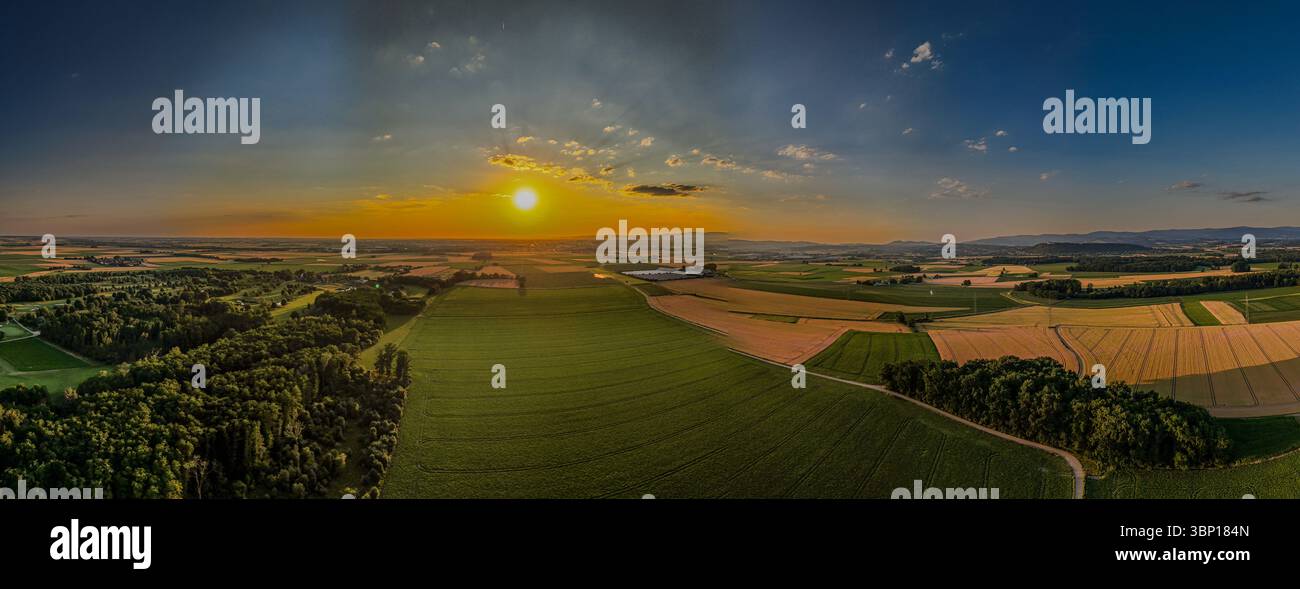 Il tramonto bagna il paesaggio bavarese inferiore con luce calda, mentre i campi e le foreste si estendono dolcemente fino all'orizzonte. Una tranquilla scena nella natura. Foto Stock