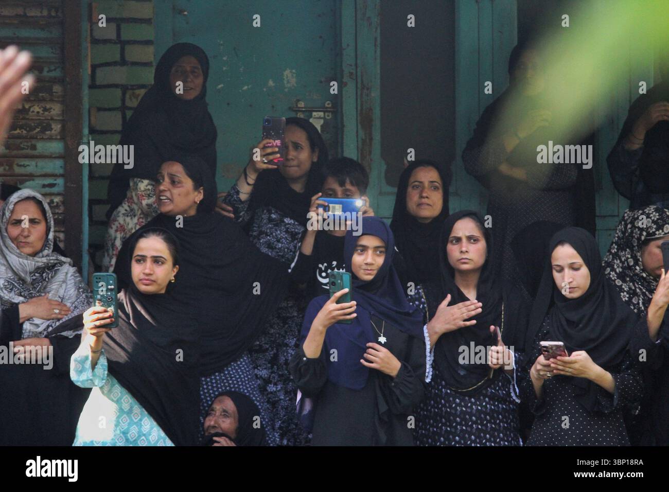 Le donne sciite kashmiri piangono osservano e registrano la processione dei 9 Muharram da una porta a Srinagar il 5 luglio 2025, durante le commemorazioni in corso dell'Ashura. Foto Stock