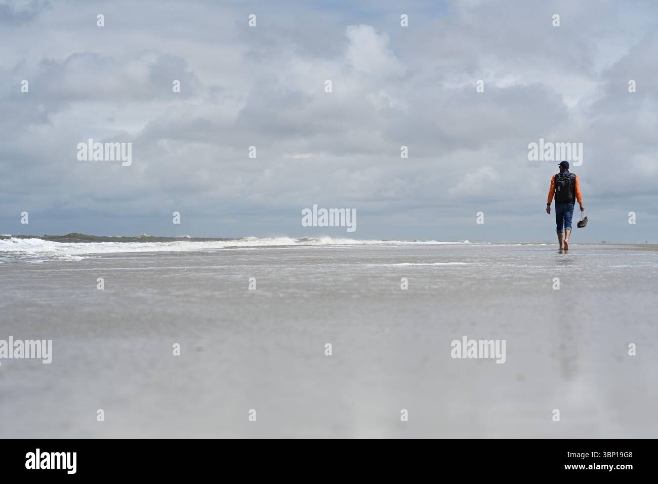 Norderney, Germania. 5 luglio 2025. Un uomo va a fare una passeggiata sulla spiaggia. All'inizio delle vacanze nella bassa Sassonia, non c'è una grande fretta sull'isola per il momento. Ci sono ancora molti angoli tranquilli lungo le spiagge. Crediti: Lars Penning/dpa/Alamy Live News Foto Stock