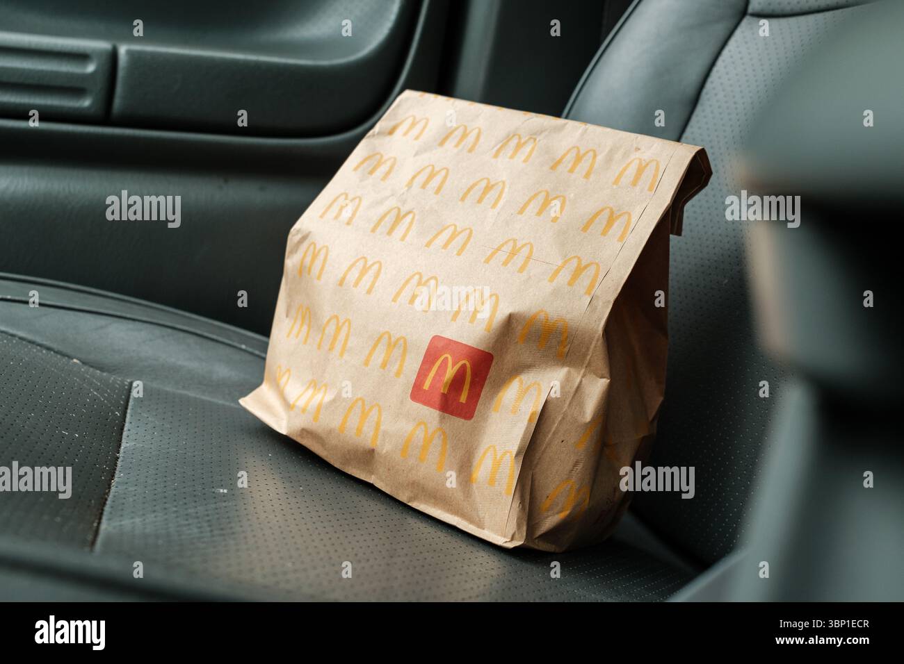 Copenaghen, Danimarca - 5 luglio 2025: Sacchetto di carta McDonald's posizionato su un seggiolino per auto per un comodo trasporto di cibo da asporto. Mangiare fast food in auto. Ill Foto Stock