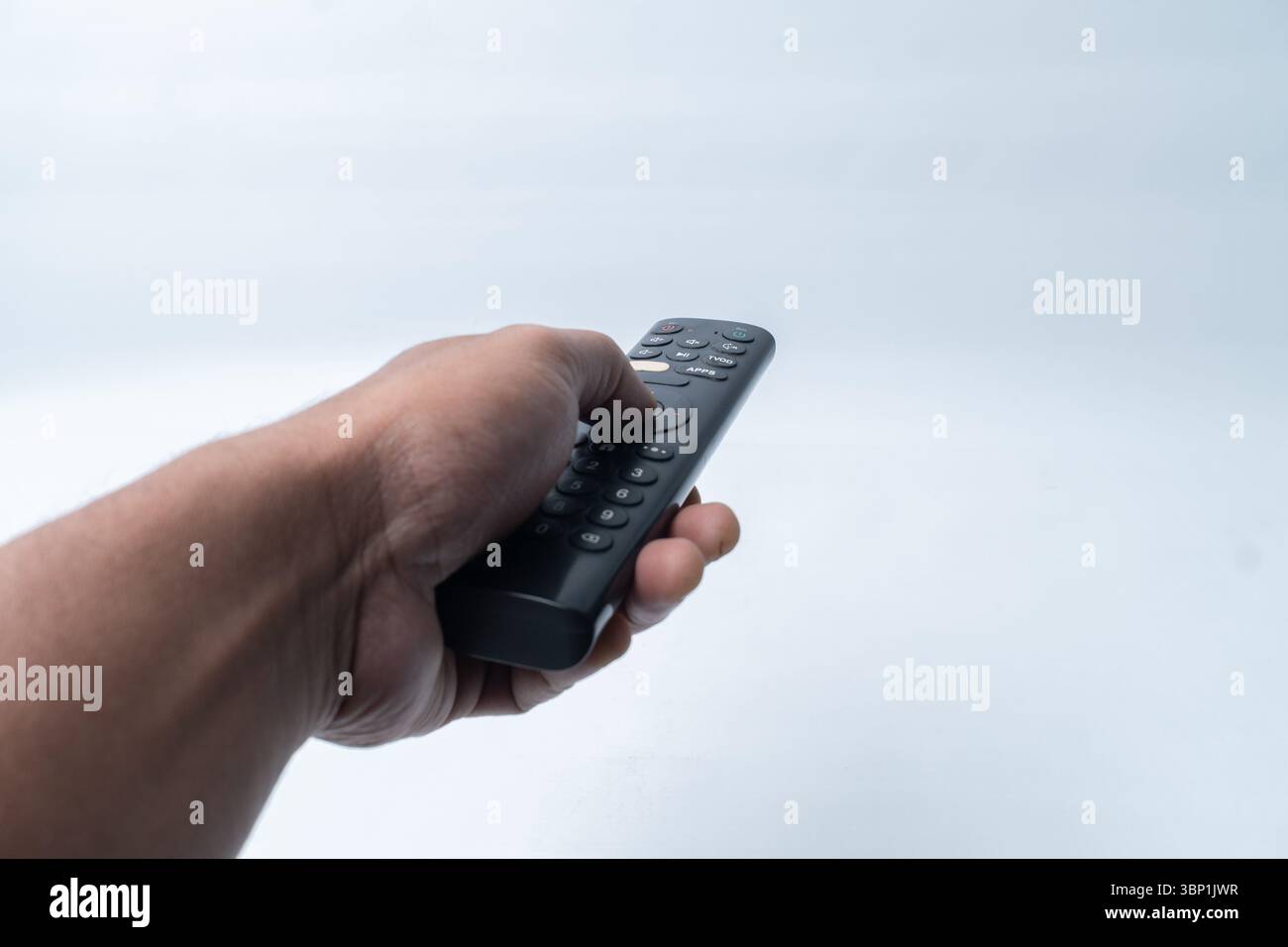Primo piano di una mano asiatica con telecomando isolato su sfondo bianco. Foto Stock