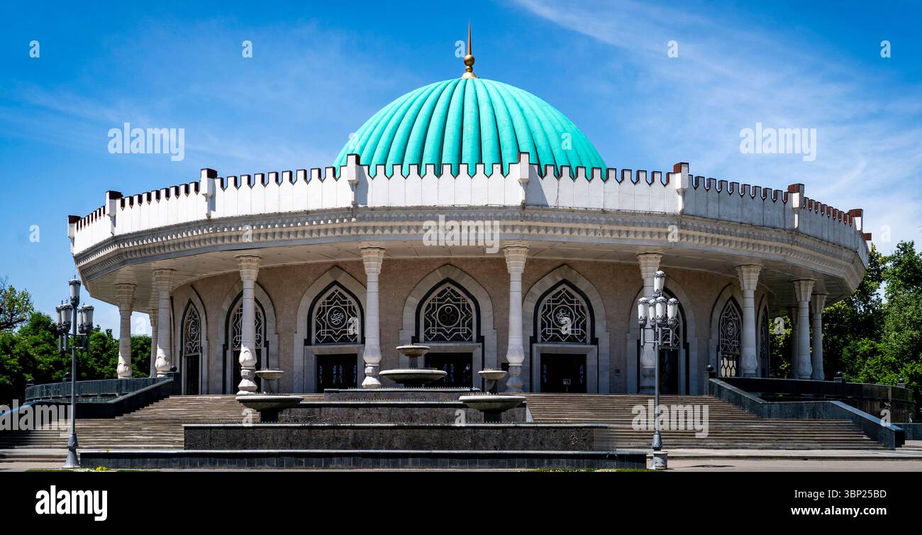 Un edificio circolare con una cupola turchese, caratterizzato da dettagli architettonici ornati e grandi finestre ad arco. La struttura e' circondata dal verde Foto Stock