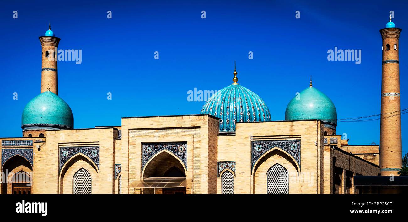 Una splendida vista architettonica di una moschea caratterizzata da cupole turchesi e alti minareti contro un cielo blu limpido. Foto Stock