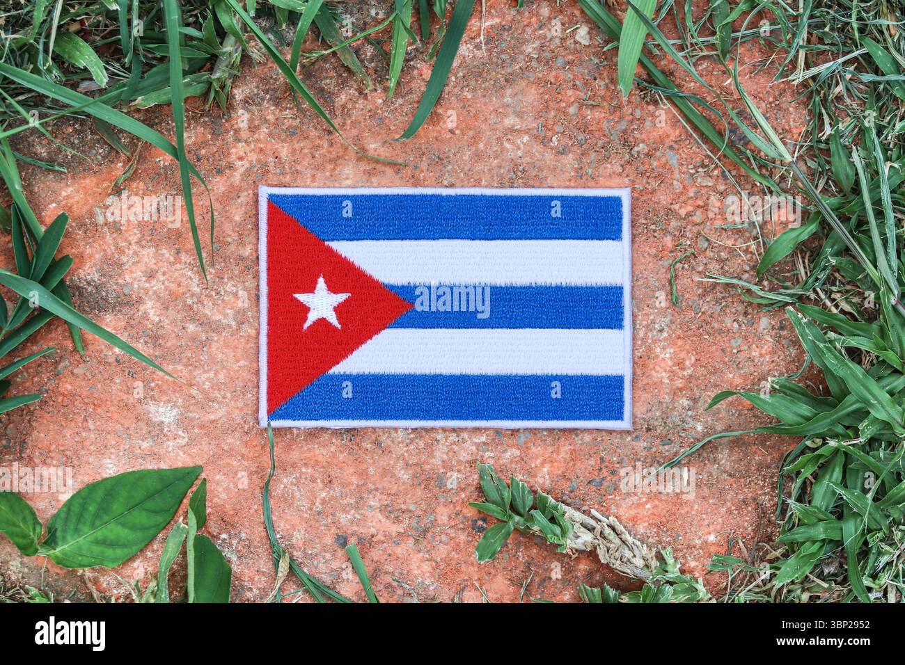 Bandiera Cuba ricamata ecologica su pietra antica con foglie naturali, simbolo del giorno della terra, della cura dell'ambiente e dell'orgoglio culturale. Foto Stock