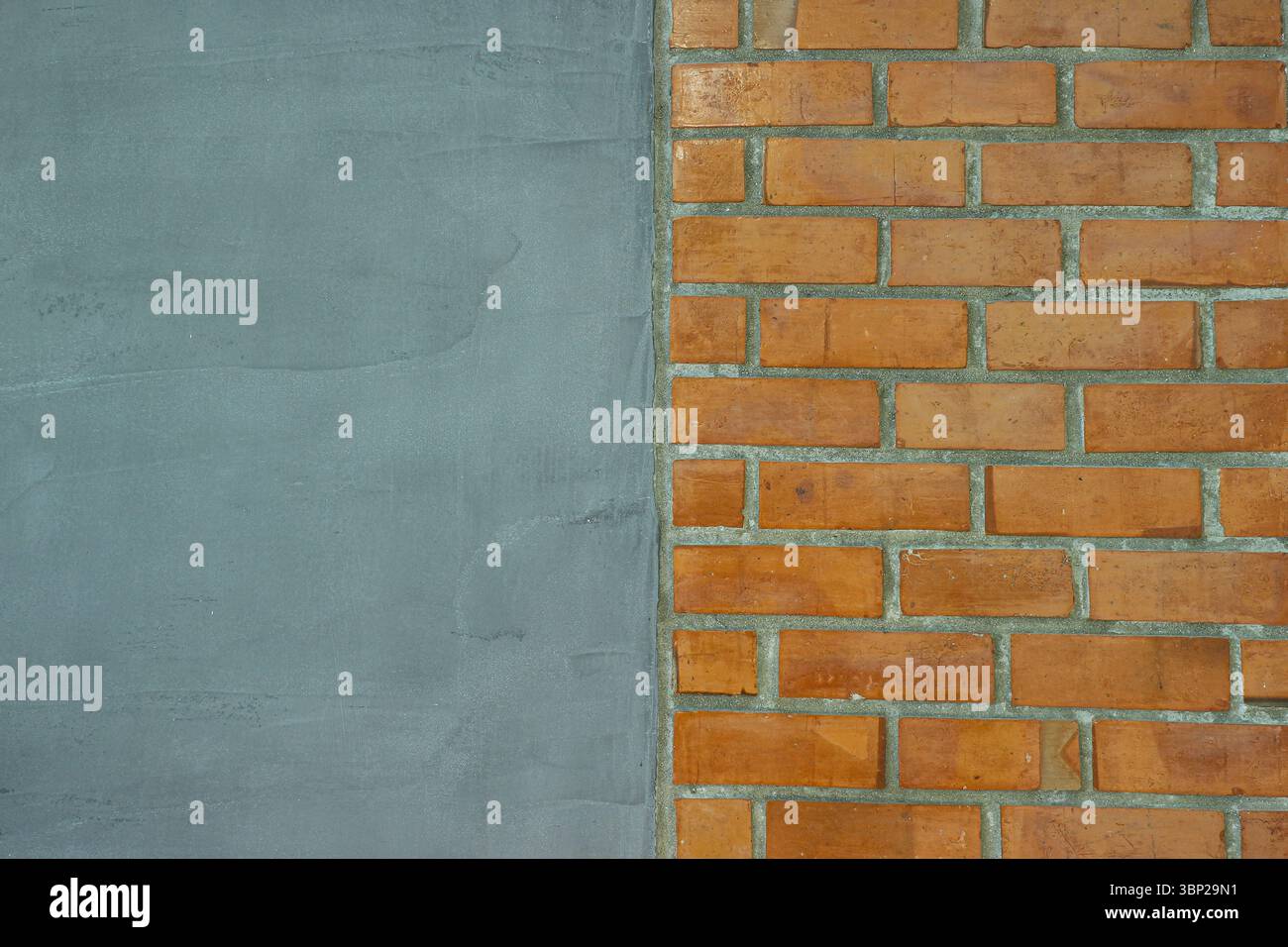 Struttura del design interno sfondo orizzontale diviso con pareti in cemento grigio liscio e motivo a blocchi in mattoni rossi, perfetto per il design astratto o la sovrapposizione di testo Foto Stock