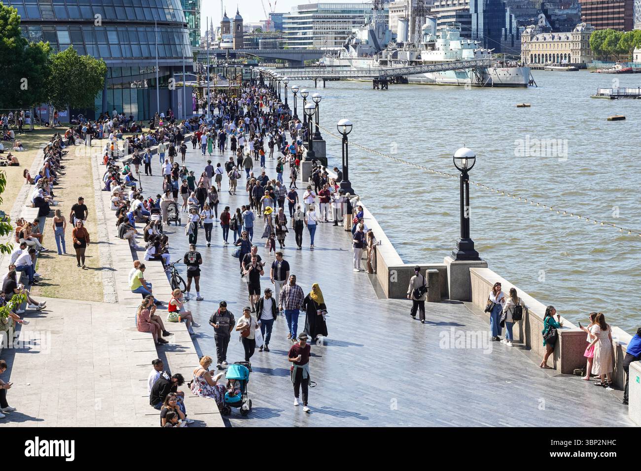 Le persone che si godono una giornata di sole al Queen's Walk Promenade a Londra, Inghilterra, Regno Unito, Regno Unito Foto Stock