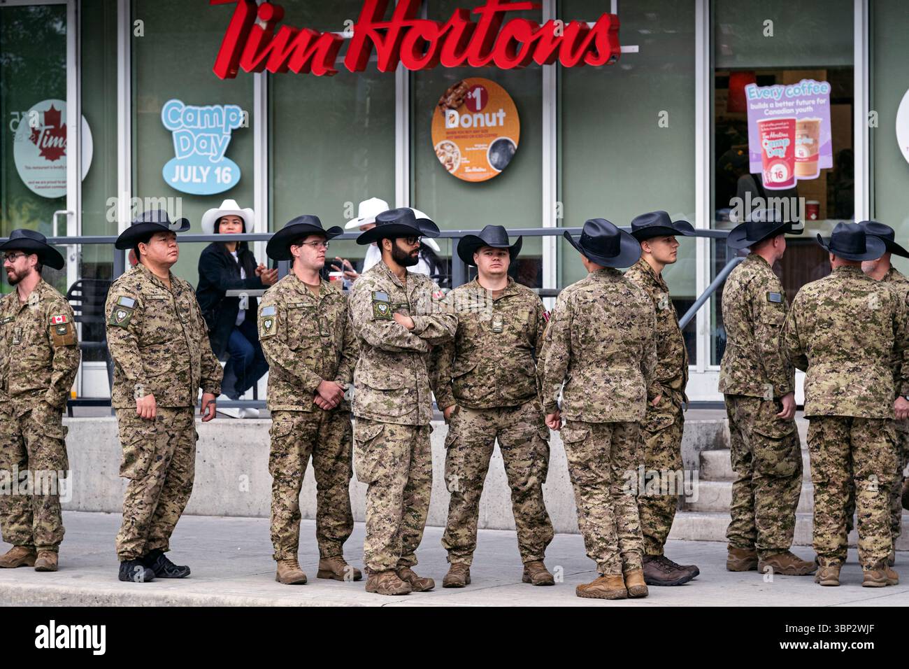 I soldati canadesi si si schierano per un caffè Tim Hortons prima dell'inizio della Calgary Stampede Parade. Alberta, Canada Foto Stock