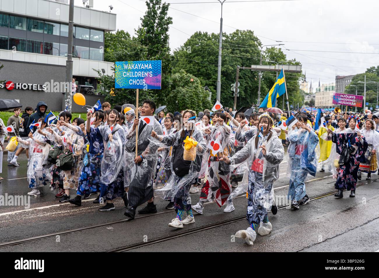 Wakayama Children’s Choir dal Giappone marciando in coloratissimi impermeabili durante la processione del Festival della canzone estone, Tallinn, Estonia, luglio 2025. Foto Stock