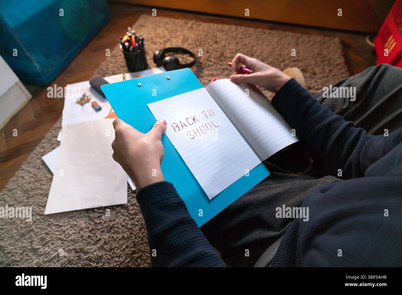 Lo studente si prepara per il ritorno a scuola, tenendo in mano un taccuino con scritto Back to School Foto Stock