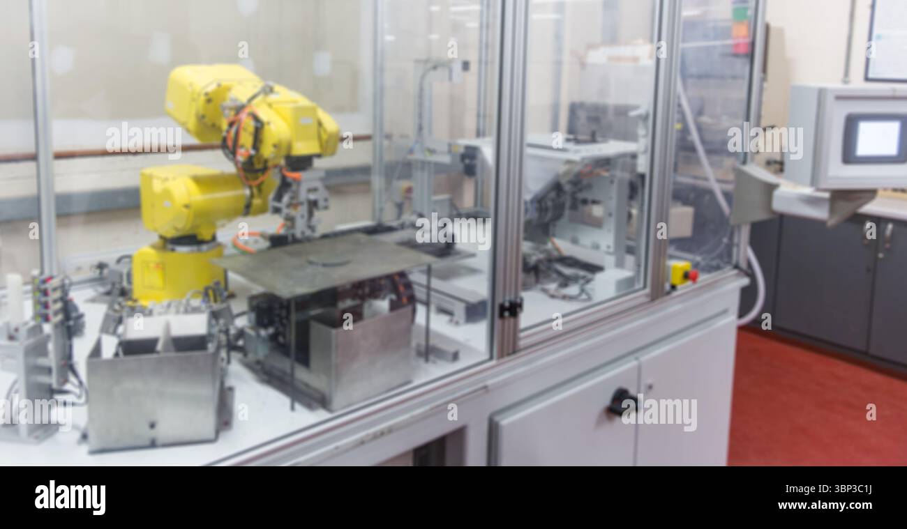 Il design piatto del braccio del robot industriale giallo funziona all'interno di un contenitore trasparente su un tavolo in metallo Foto Stock