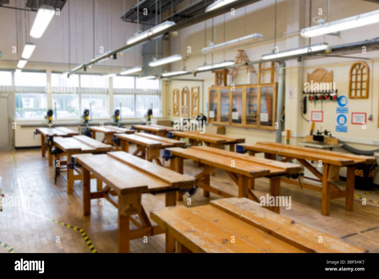 Officina di progettazione piatta che mostra file di banchi con morse e utensili elettrici sotto i finestrini Foto Stock