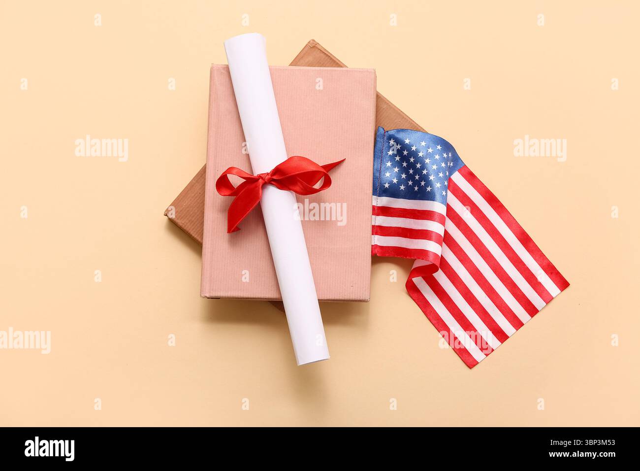 Diploma con nastro rosso, bandiera USA e libro su sfondo beige Foto Stock