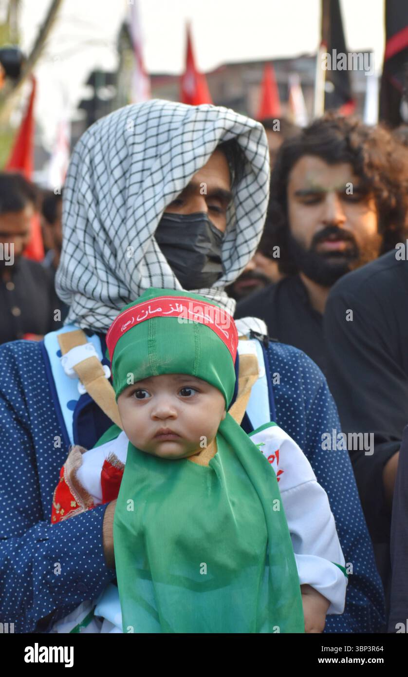 Processione dell'ottavo Muharram nel Kashmir India Un uomo sciita del Kashmir tiene il suo bambino vestito in abiti tradizionali durante la processione di Muharram, simboleggiando lo spirito di sacrificio e il ricordo del martirio dell'imam Hussain. Il 4 luglio 2025 a Srinagar, India. Srinagar Jammu e kashmir India Copyright: XUmerxQadirx Foto Stock