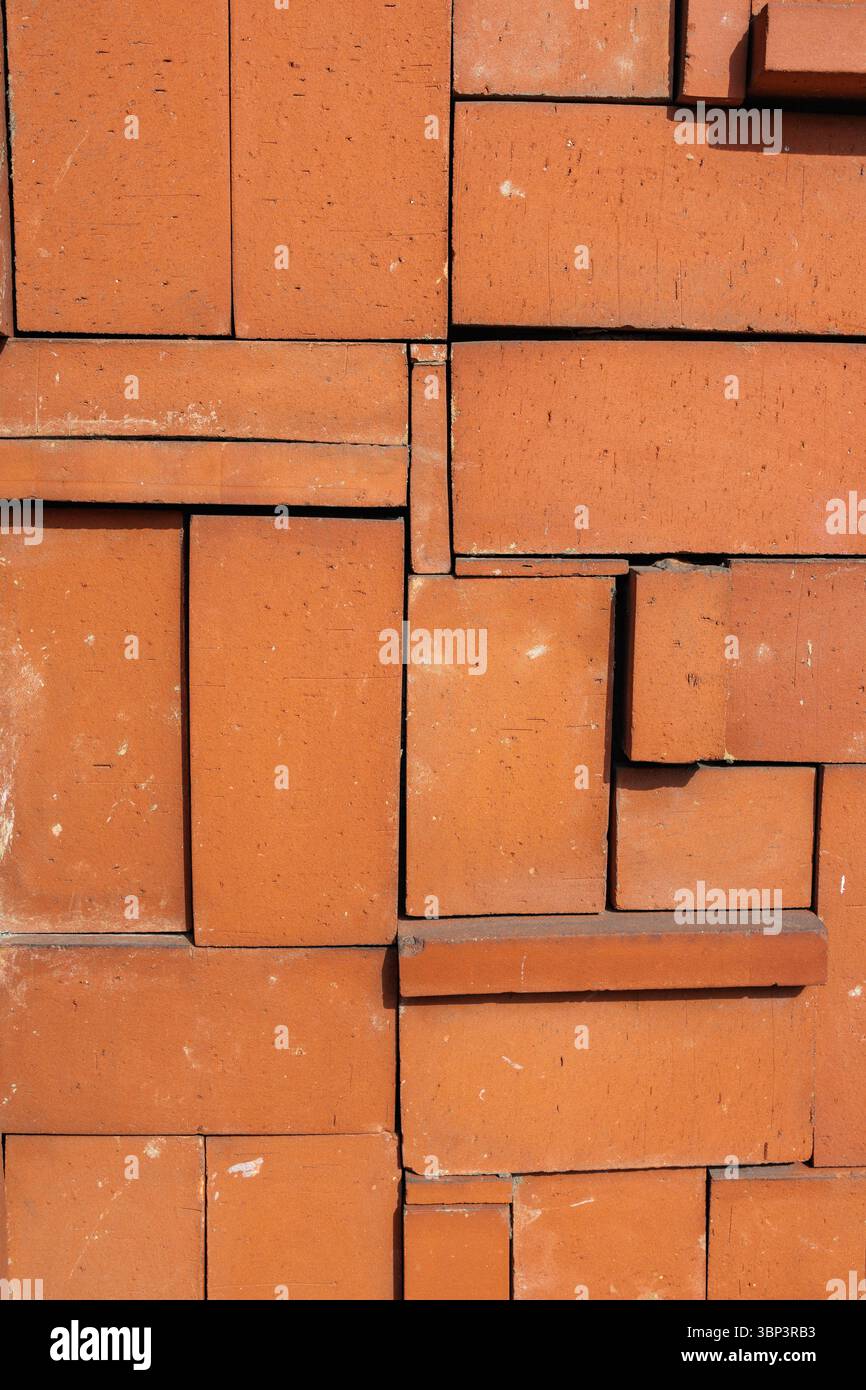 I mattoncini di ricottura impilati in modo ordinato formano pareti geometricamente casuali e visivamente accattivanti. I toni terrosi dei mattoni ne esaltano la texture, aggiungendo una sensazione naturale. Foto Stock