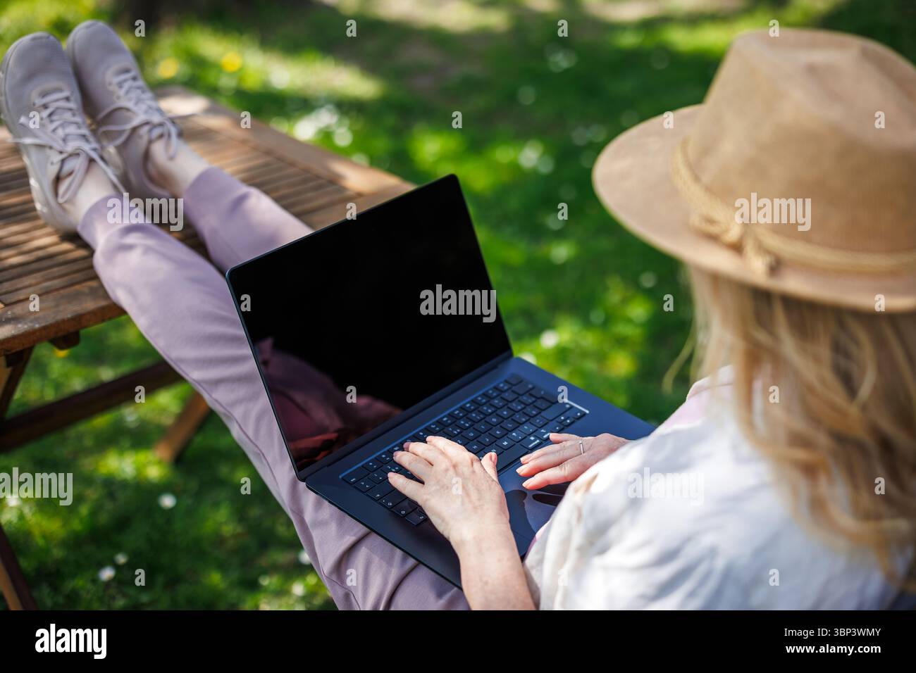 Donna che usa un notebook all'aperto. Telelavoro dal parco. Concetto di lavoro freelance e lavoro in remoto Foto Stock