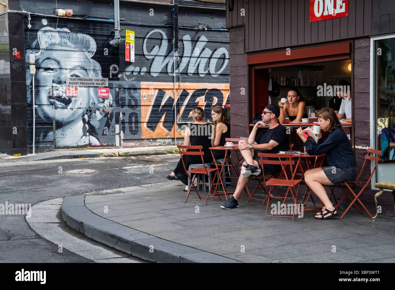 Un caffè all'angolo accanto a un murale di Marilyn Monroe con denti di vampiro a Kings Cross, Sydney, Australia Foto Stock