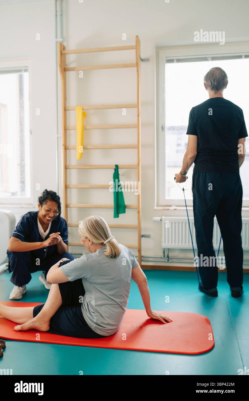 Terapeuta con pazienti anziani che esercitano presso il centro di riabilitazione Foto Stock