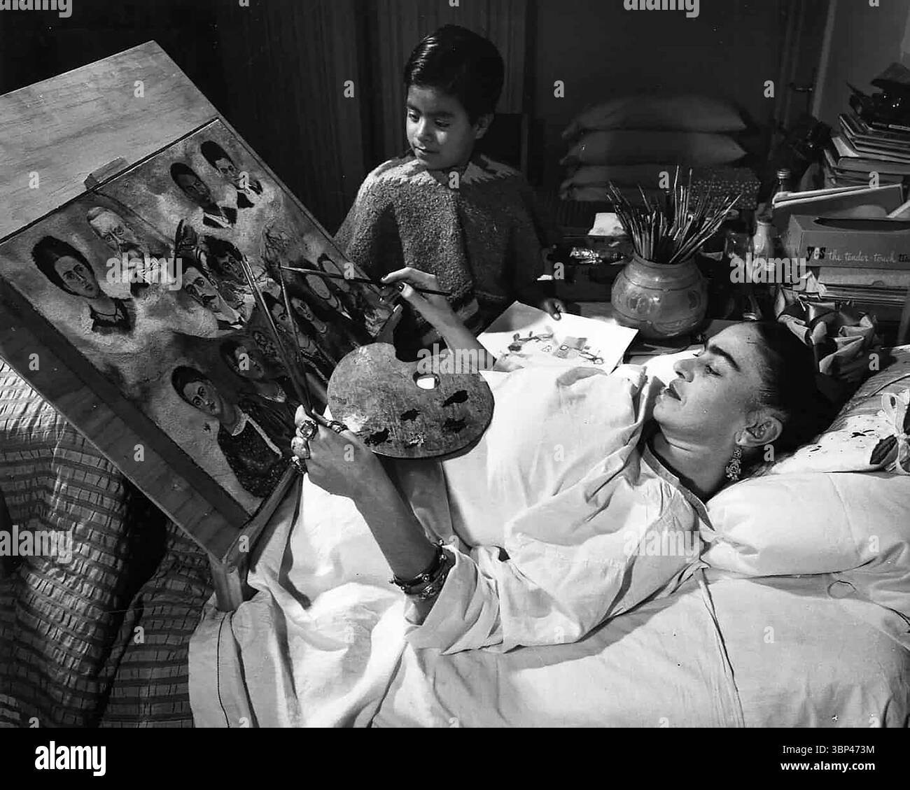 Una fotografia di Frida Kahlo che dipinge a letto. Frida Kahlo soffrì di dolore cronico durante la sua vita adulta a causa di un grave incidente in autobus nel 1925 e di altri problemi di salute, tra cui la poliomielite nella sua infanzia. Ha trascorso più di un anno a letto riprendendo da fratture alla colonna vertebrale, alla clavicola e alle costole, a un bacino frantumato e a lesioni alle spalle e ai piedi. Ha sopportato più di 30 operazioni durante la sua vita e durante la sua convalescenza ha iniziato a dipingere. Gran parte della sua produzione artistica è stata creata dal suo letto, trasformando la sua sofferenza fisica in potenti narrazioni visive. Foto Stock