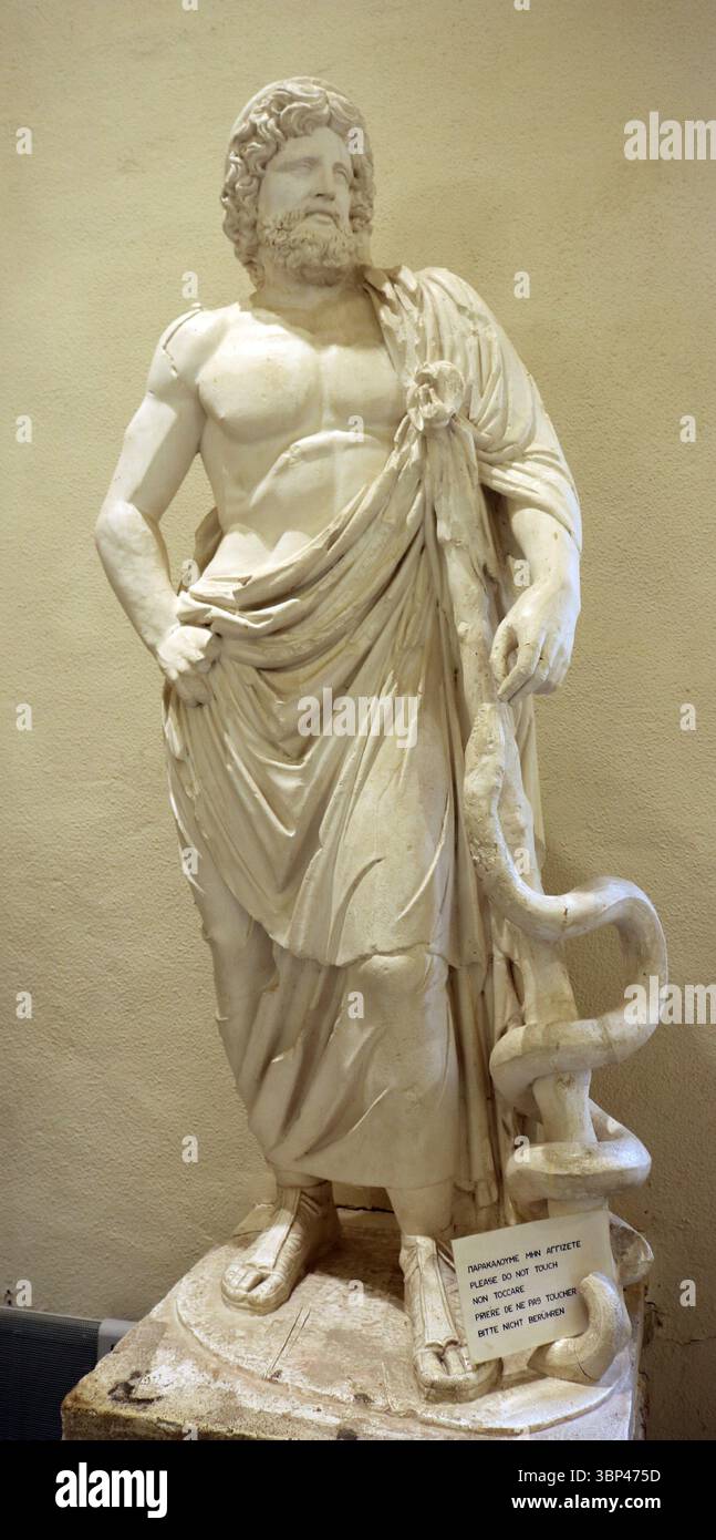 Una fotografia di una statua romana in marmo di Asclepio, con il suo bastone intrecciato da serpenti, Museo Archeologico di Epidauro. Dal Santuario di Asclepio in Epidauro. Specialmente nel periodo classico ed ellenistico, era il principale sito sacro di Asclepio. Il santuario di Epidauro era il rivale di importanti siti di culto come il Santuario di Zeus ad Olimpia e Apollo a Delfi. Il tempio fu costruito all'inizio del IV secolo a.C. Se ancora in uso nel IV secolo d.C., il tempio sarebbe stato chiuso durante la persecuzione dei pagani nel tardo Impero Romano, quando gli imperatori cristiani lo emettero Foto Stock