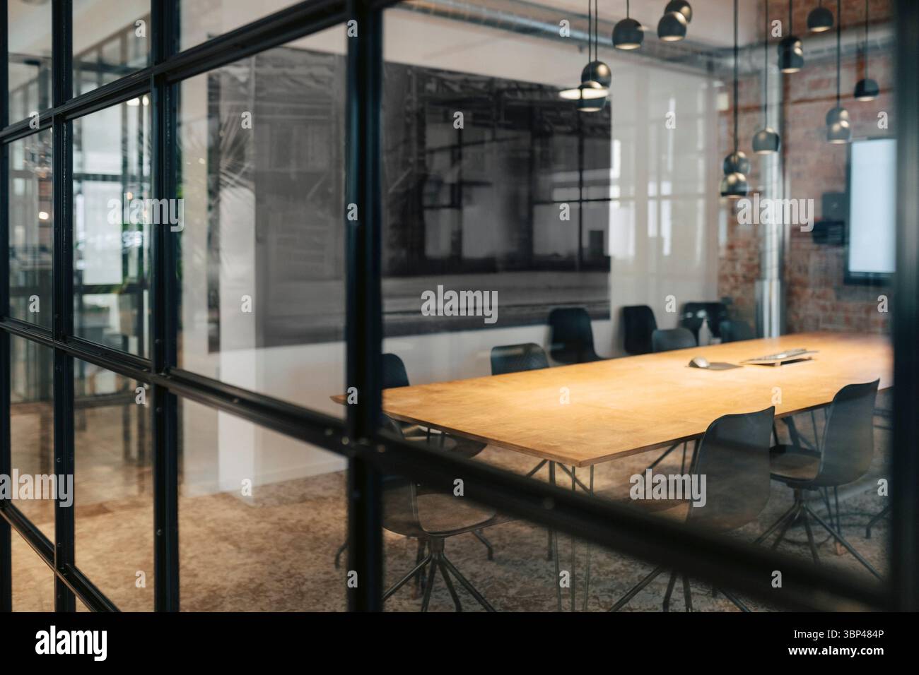 Sala conferenze illuminata con sedie e tavolo visibile attraverso una parete di vetro Foto Stock