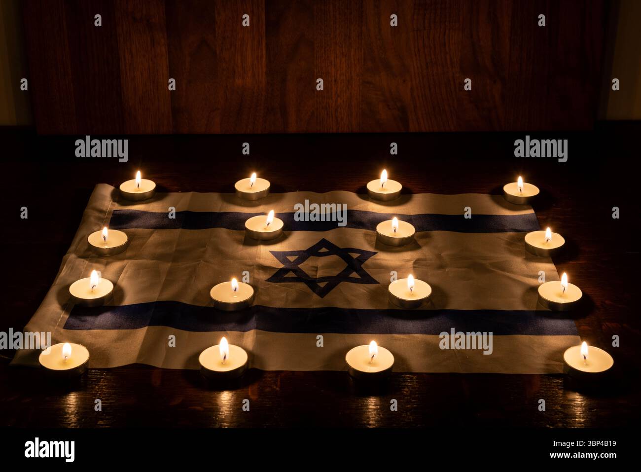 Candele commemorative che brillano su una bandiera israeliana per celebrare le festività ebraiche di Yom HaZikaron, Memorial Day e Holocaust Remembrance Day in Israele. Foto Stock