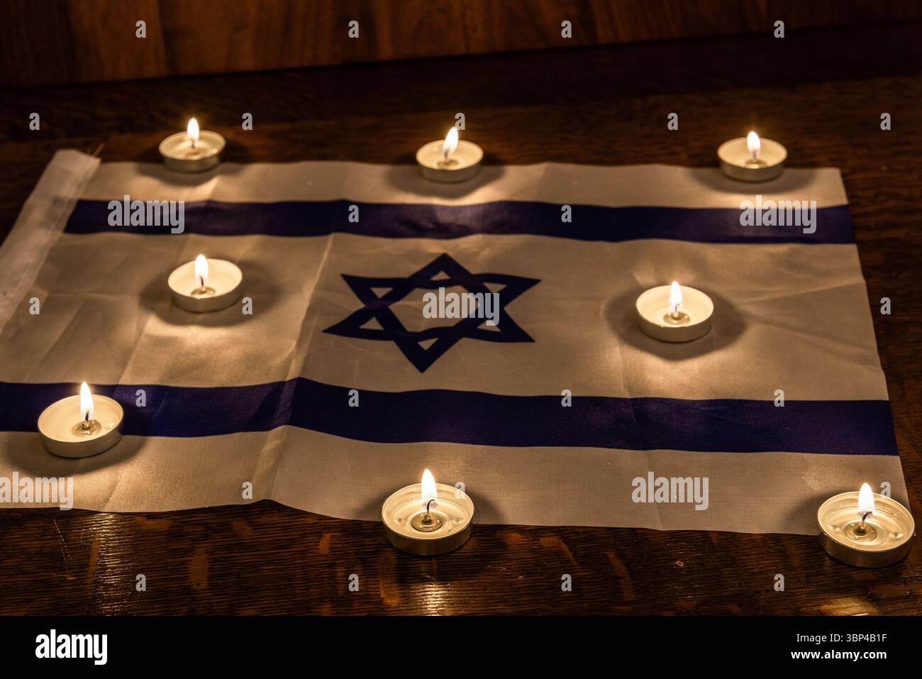 Candele commemorative che brillano su una bandiera israeliana per celebrare le festività ebraiche di Yom HaZikaron, Memorial Day e Holocaust Remembrance Day in Israele. Foto Stock
