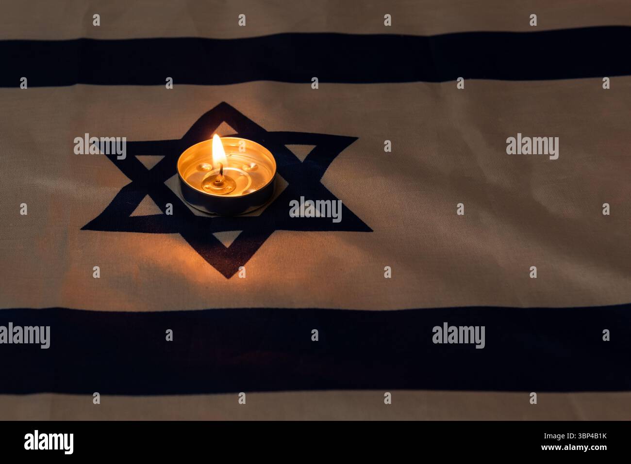 Una candela commemorativa illuminata su una bandiera israeliana per celebrare le festività ebraiche di Yom HaZikaron, Memorial Day e Holocaust Remembrance Day in Israele. Foto Stock