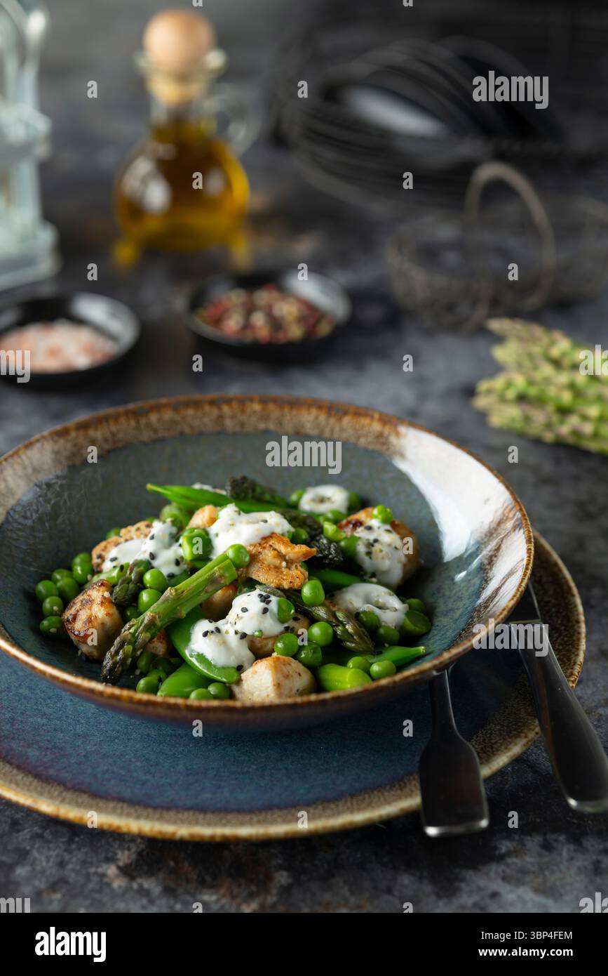 Piatto elegante con capesante, asparagi e salsa cremosa su un tavolo rustico Foto Stock