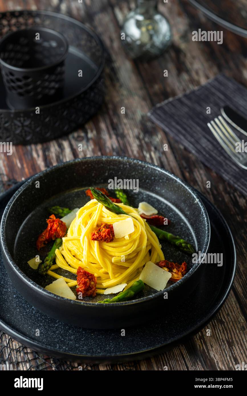 Elegante piatto di pasta con formaggio e decorazioni colorate su tavola rustica Foto Stock
