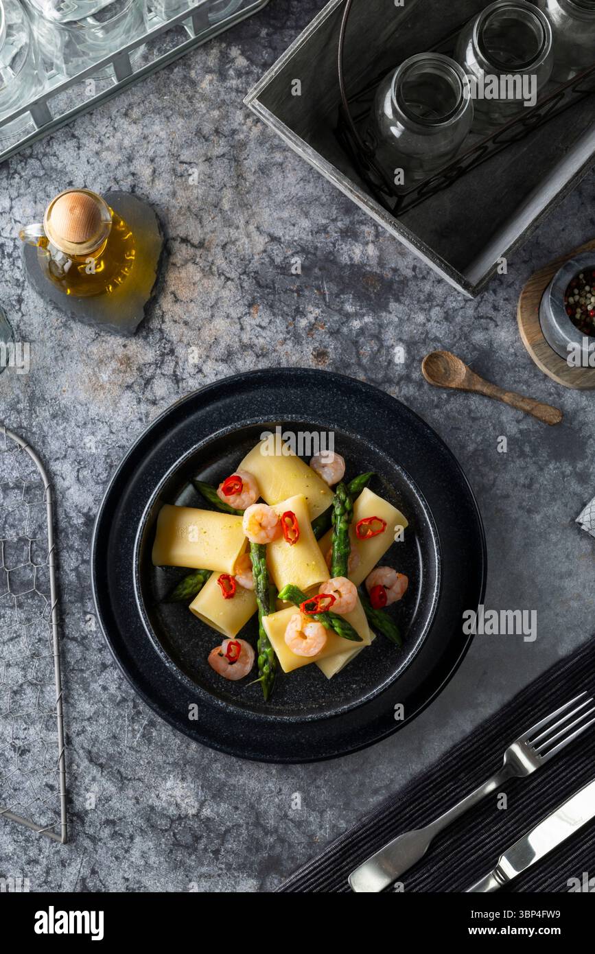 Piatto elegante con pasta, gamberi e asparagi su sfondo testurizzato Foto Stock