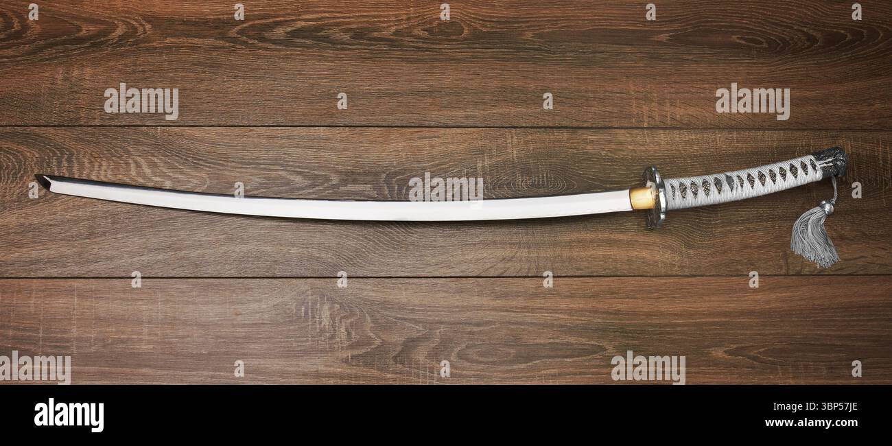 Katana, spada giapponese, su uno sfondo di legno Foto Stock