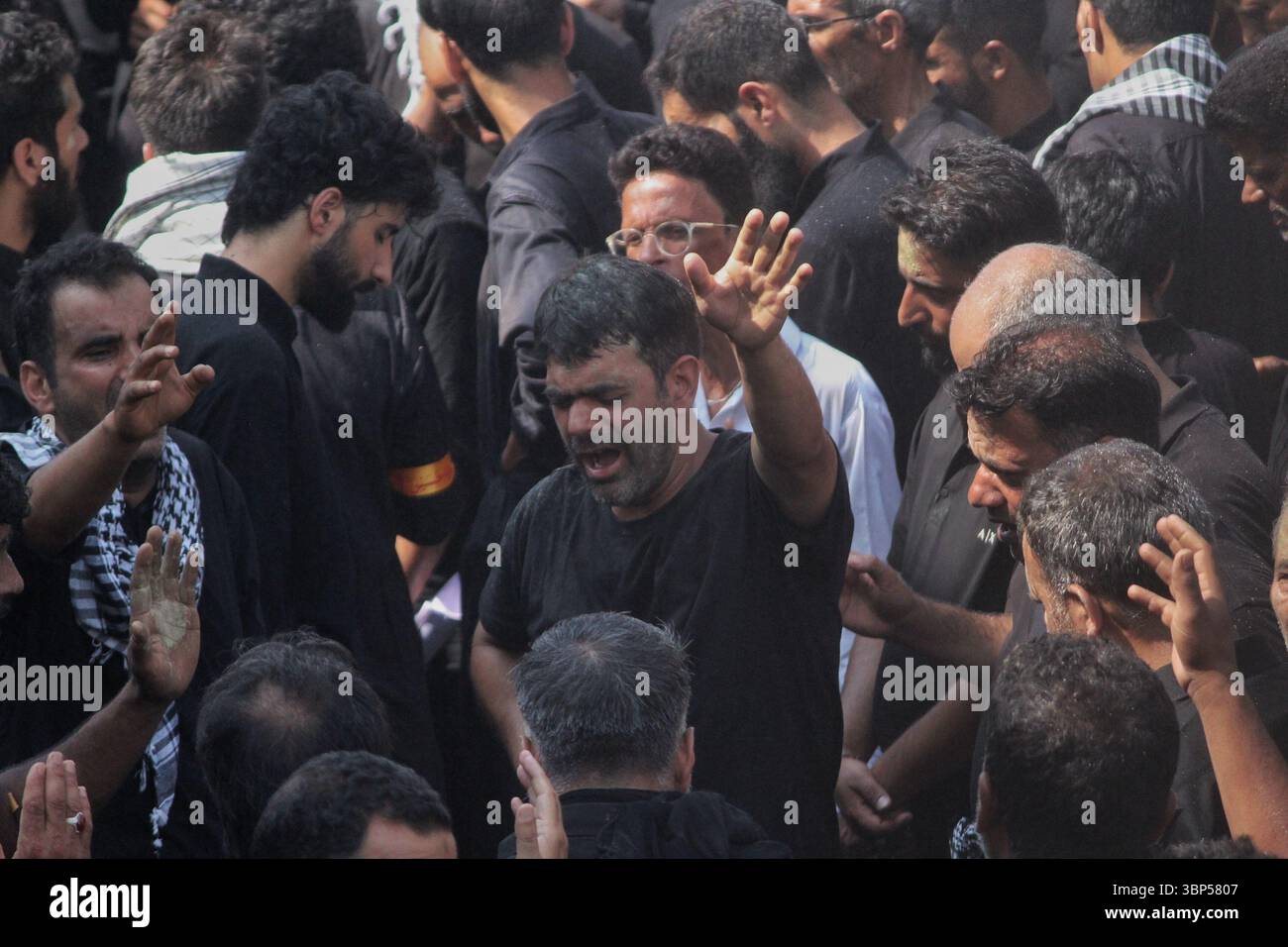 Un musulmano sciita kashmiri solleva la mano nel dolore mentre i lori si radunano durante la decima processione Muharram a Srinagar il 6 luglio 2025, segnando il martirio dell'imam Hussain. Foto Stock